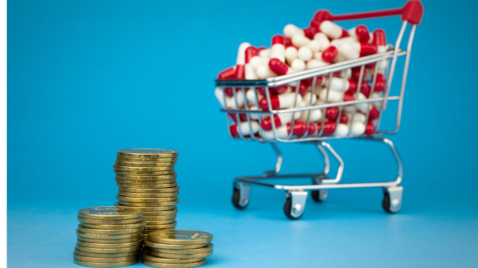 Carrinho de compras cheio de remédios e várias moedas significando o preço de compra. Foto: Canva